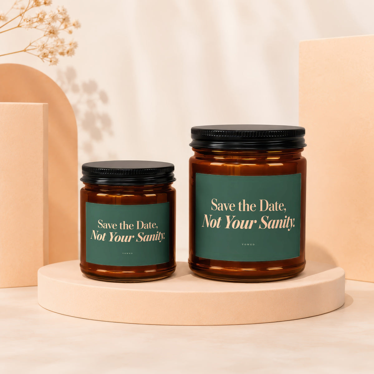 Two amber glass candles with dark lids and green labels reading "Save the Date, Not Your Sanity."