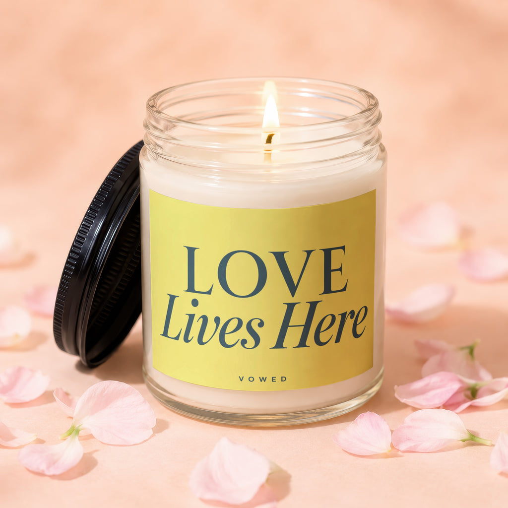Candle with lit wick and yellow label that says "LOVE Lives Here".
