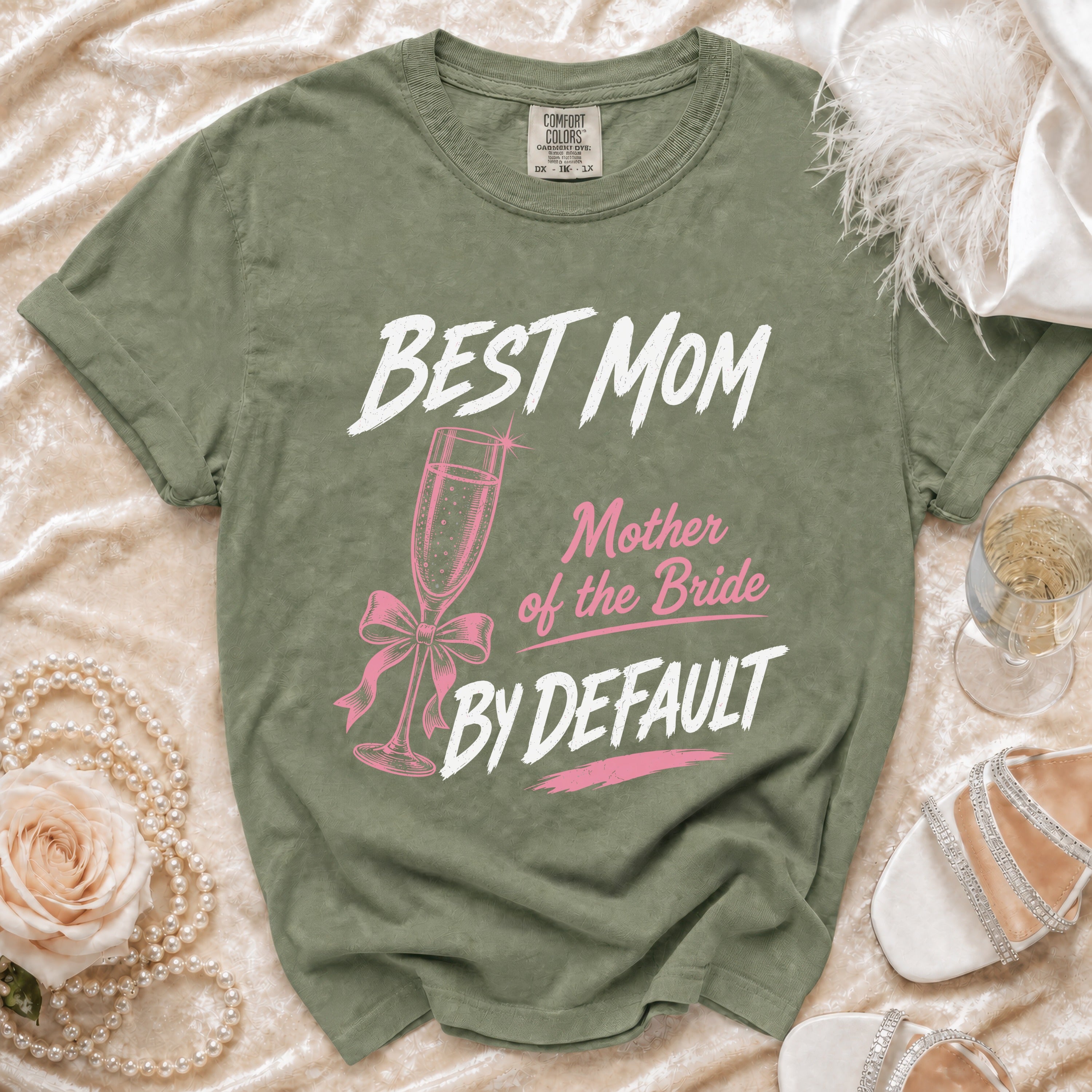 Olive green t-shirt with "BEST MOM Mother of the Bride BY DEFAULT" text and champagne flute graphic.