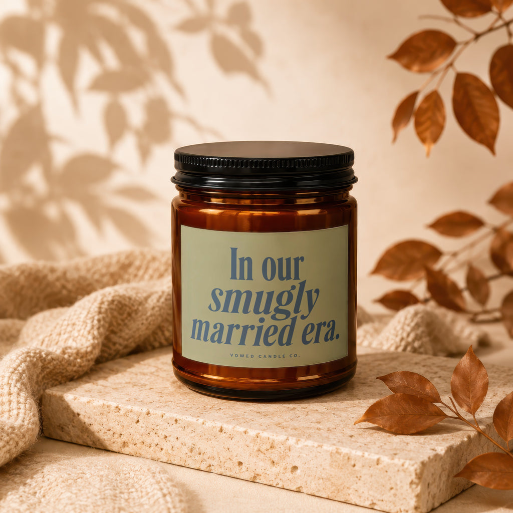 Amber candle in jar with black lid labeled "In our smugly married era. VOWED CANDLE CO."