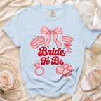 Light blue Comfort Colors t-shirt with "Bride To Be" and bridal icons in red.