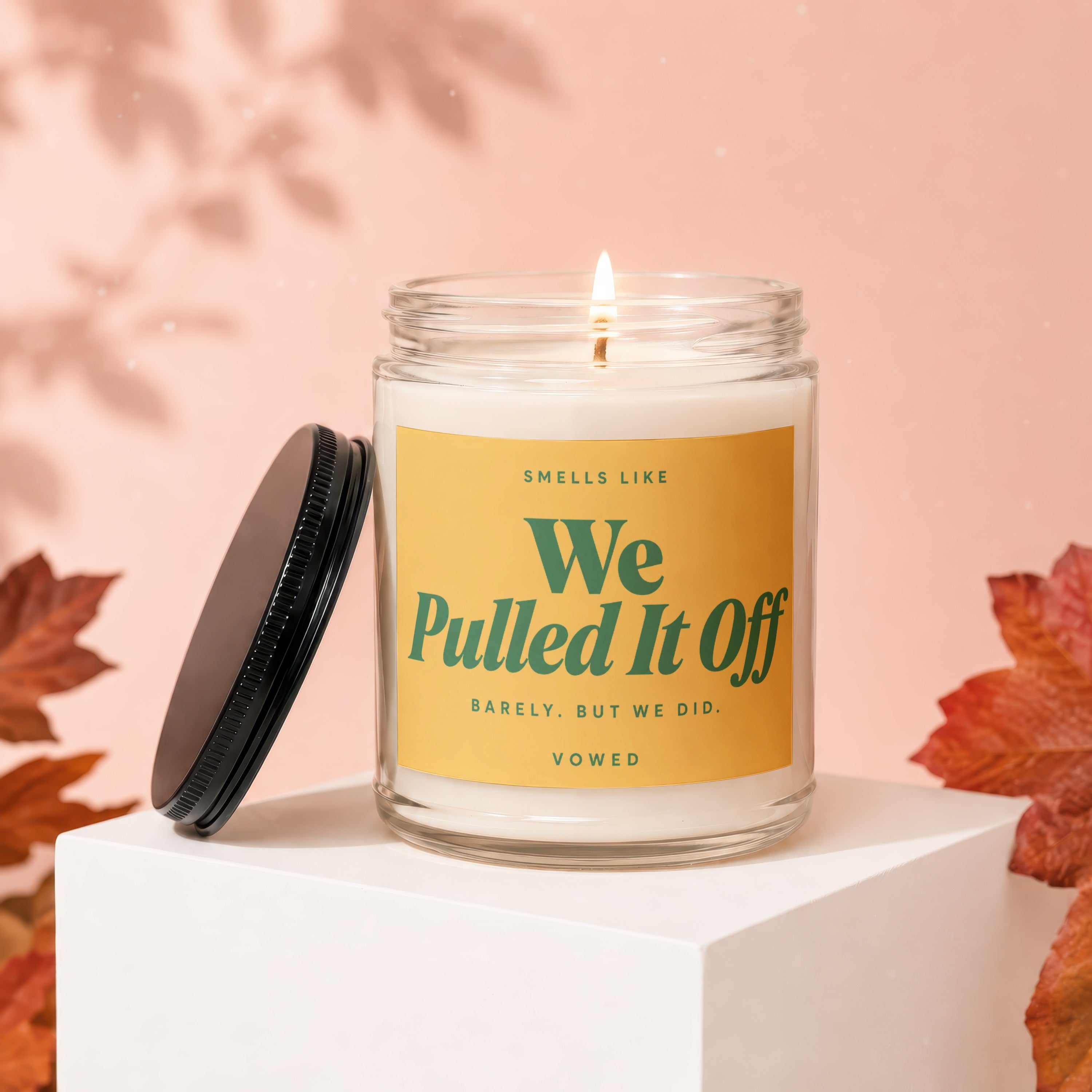 Candle with yellow label that says "Smells Like We Pulled It Off".