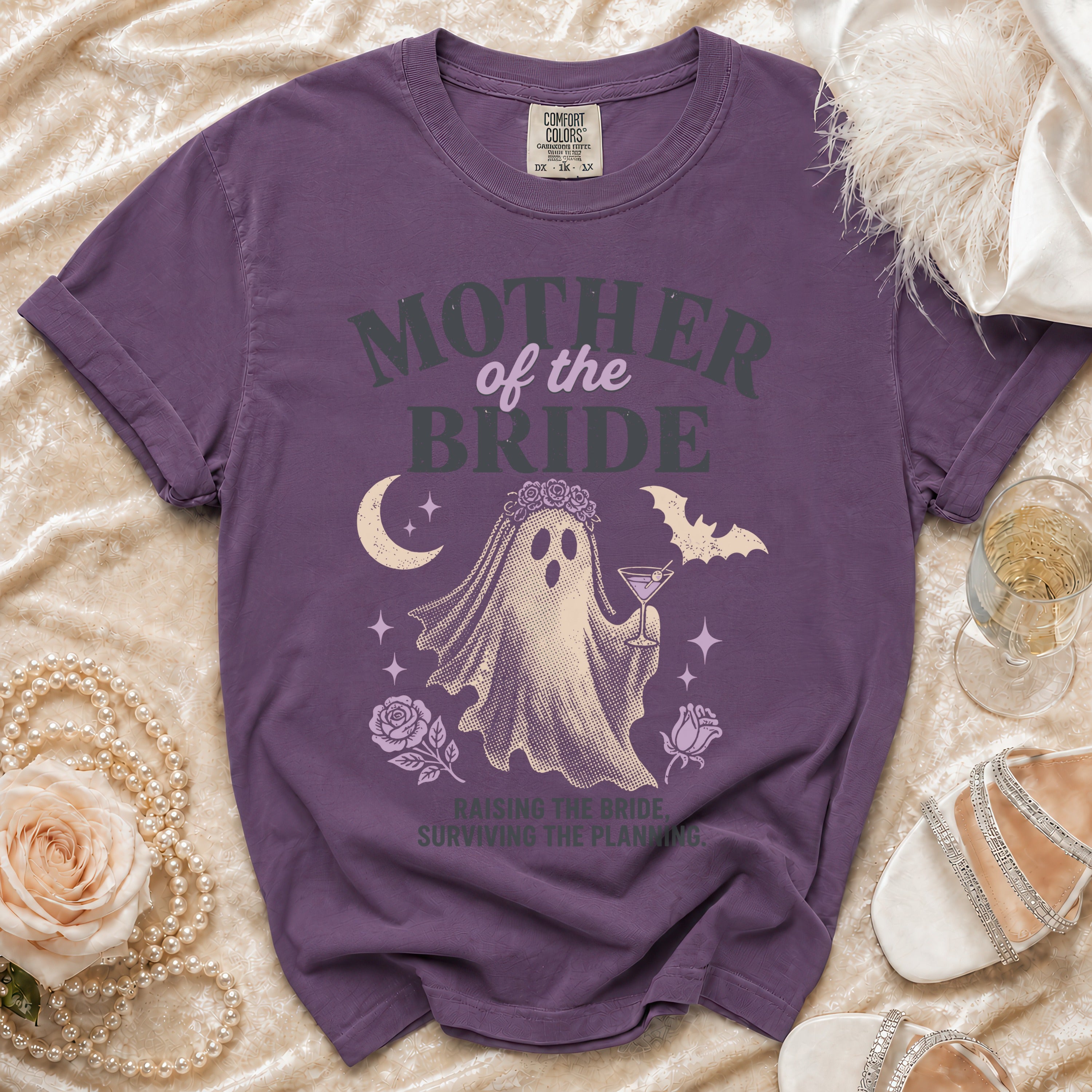 Purple t-shirt with "Mother of the Bride" text, ghost graphic, and "Raising the Bride, Surviving the Planning" tagline.