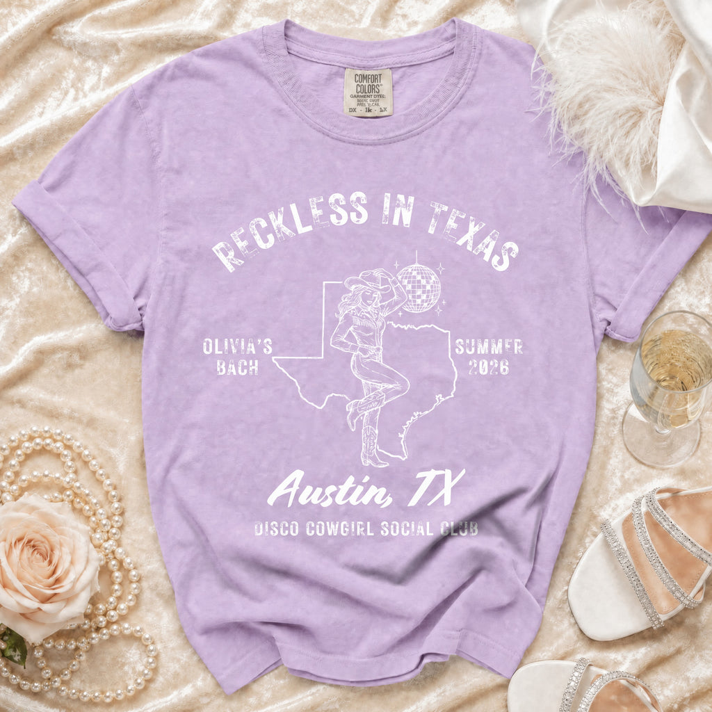 Purple t-shirt with "Reckless in Texas" and disco cowgirl design.