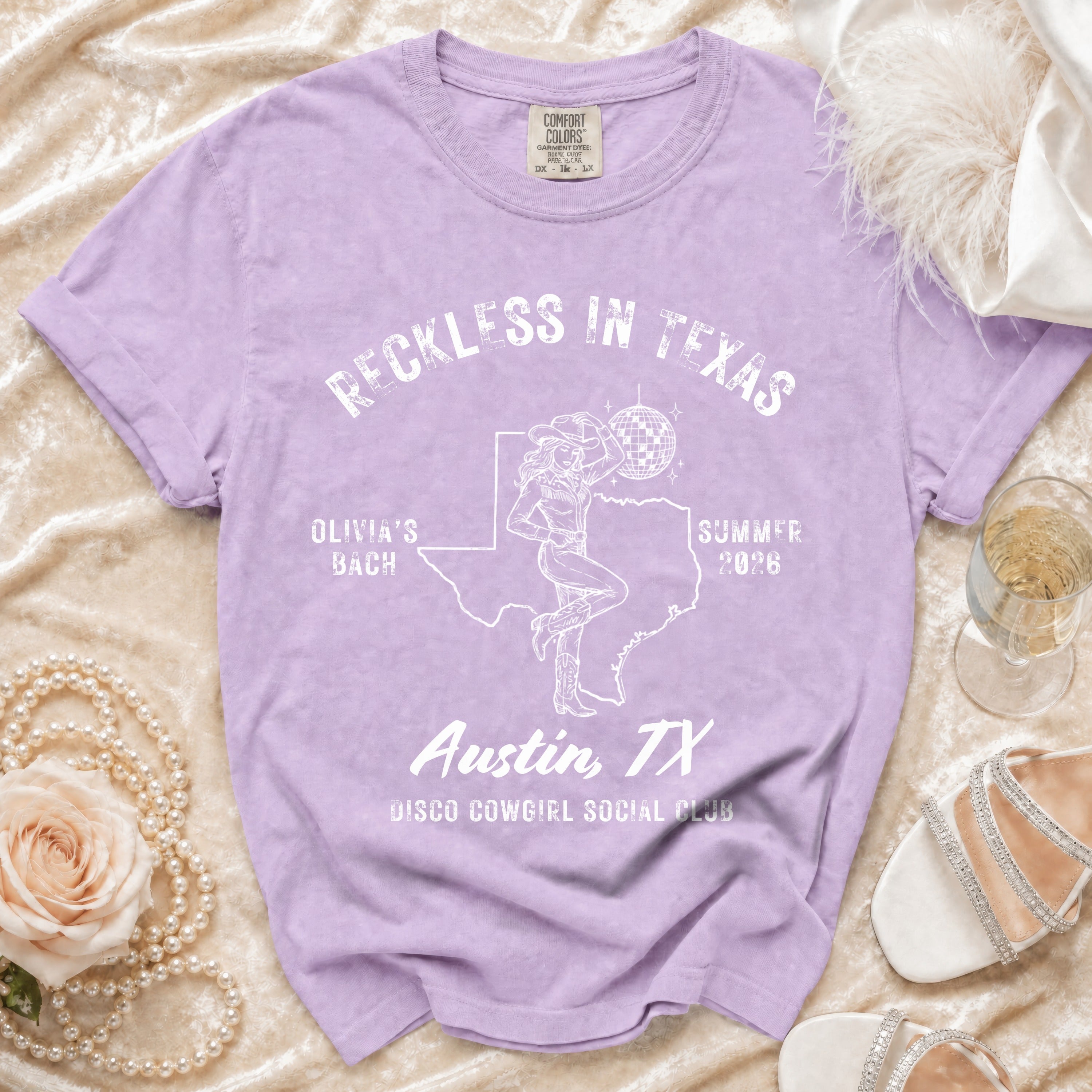 Purple t-shirt with "Reckless in Texas" and disco cowgirl design.