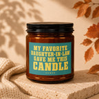 Amber glass candle with a teal label that says "MY FAVORITE DAUGHTER-IN-LAW GAVE ME THIS CANDLE".