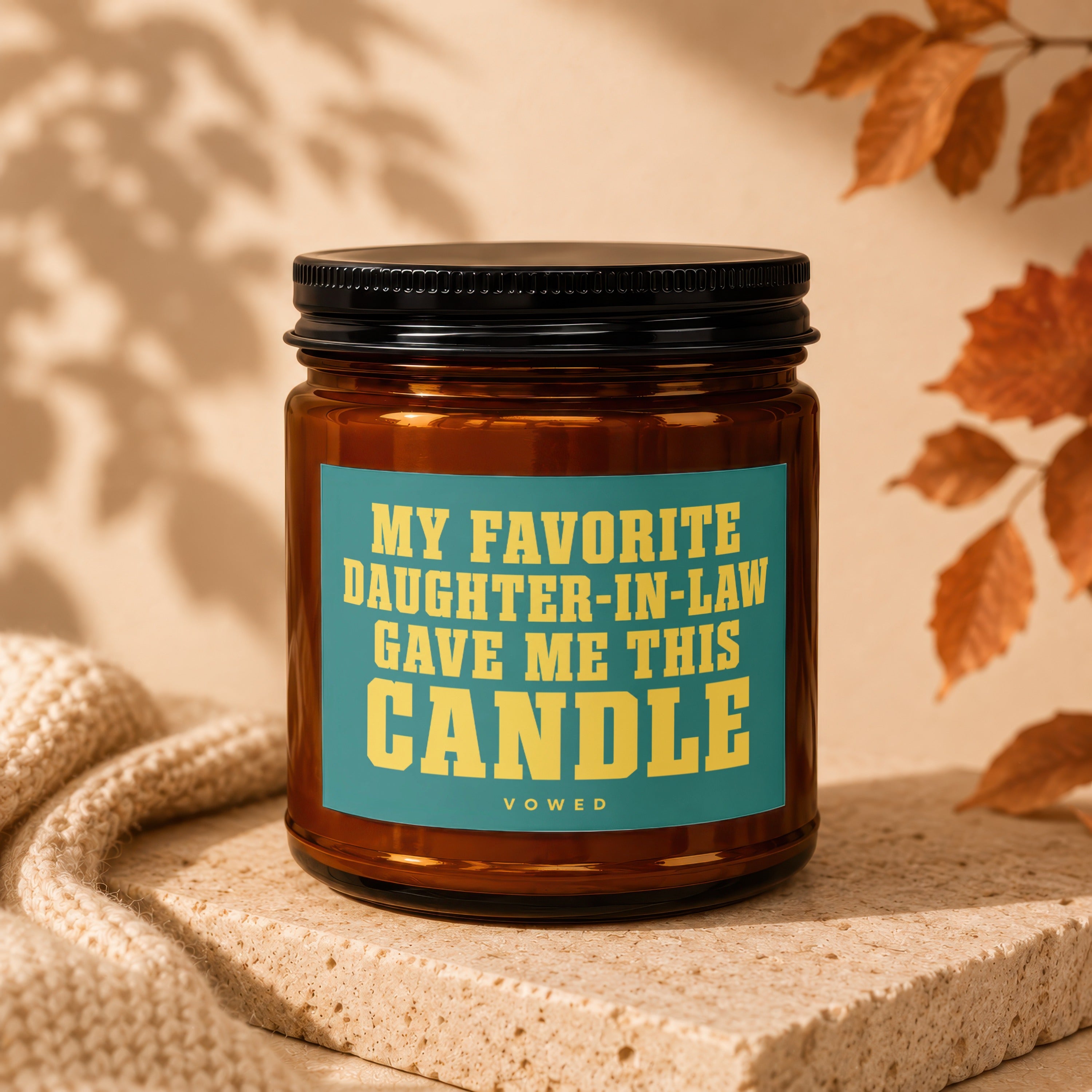 Amber glass candle with a teal label that says "MY FAVORITE DAUGHTER-IN-LAW GAVE ME THIS CANDLE".