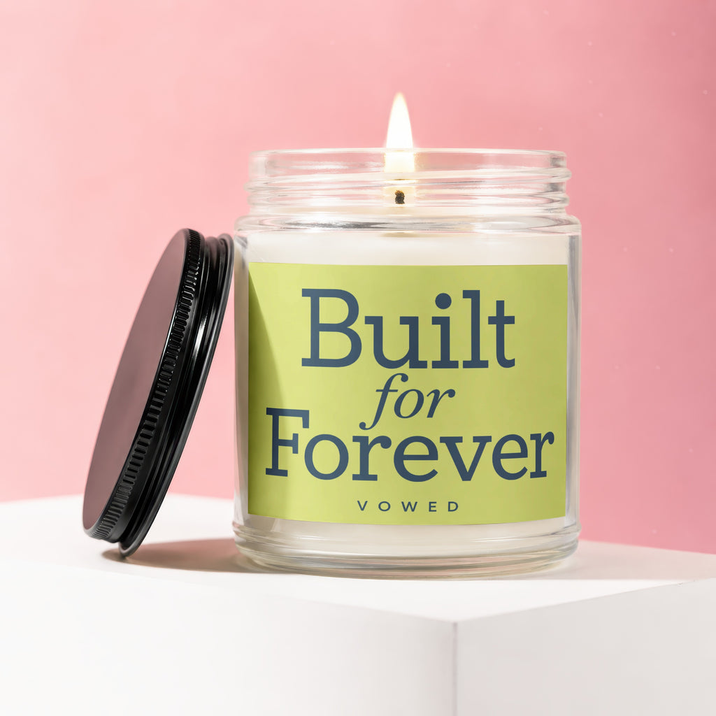 Glass candle with lit wick, featuring "Built for Forever" text on a green label.