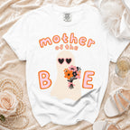 White t-shirt with "mother of the B E" text, ghost graphic, and floral bouquet.