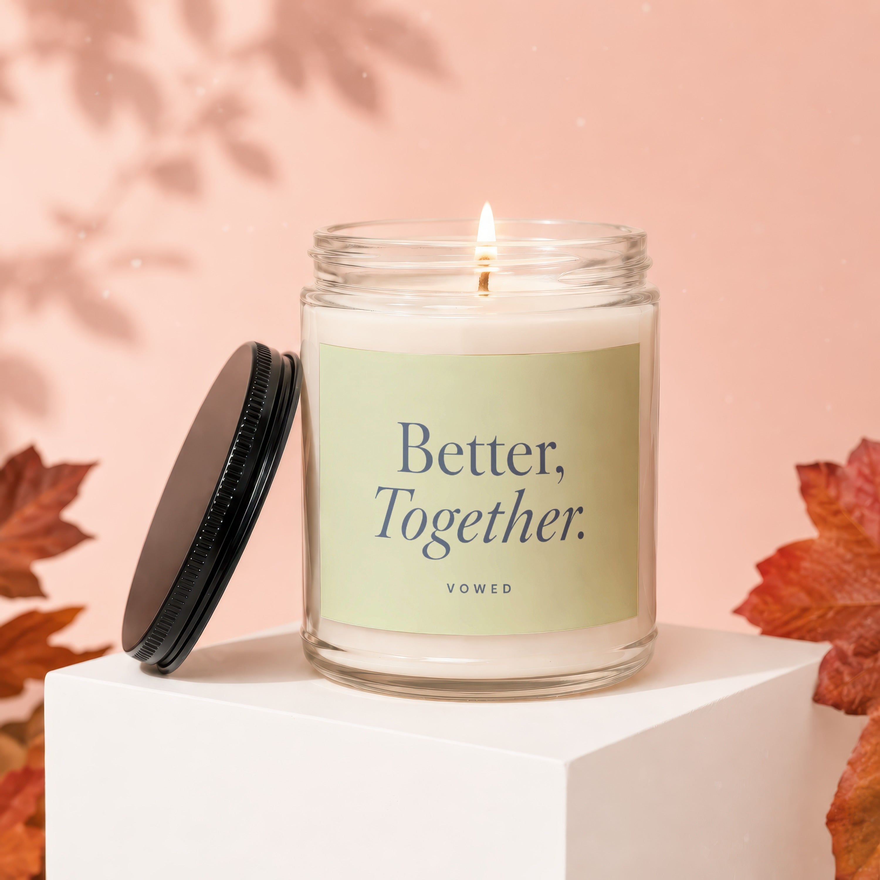 Glass candle with lit wick and "Better, Together. vowed" text on a light green label.