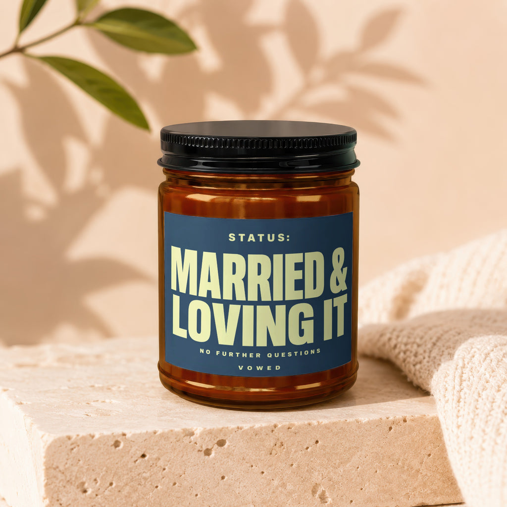 Amber jar candle with dark lid, labeled "STATUS: MARRIED & LOVING IT".