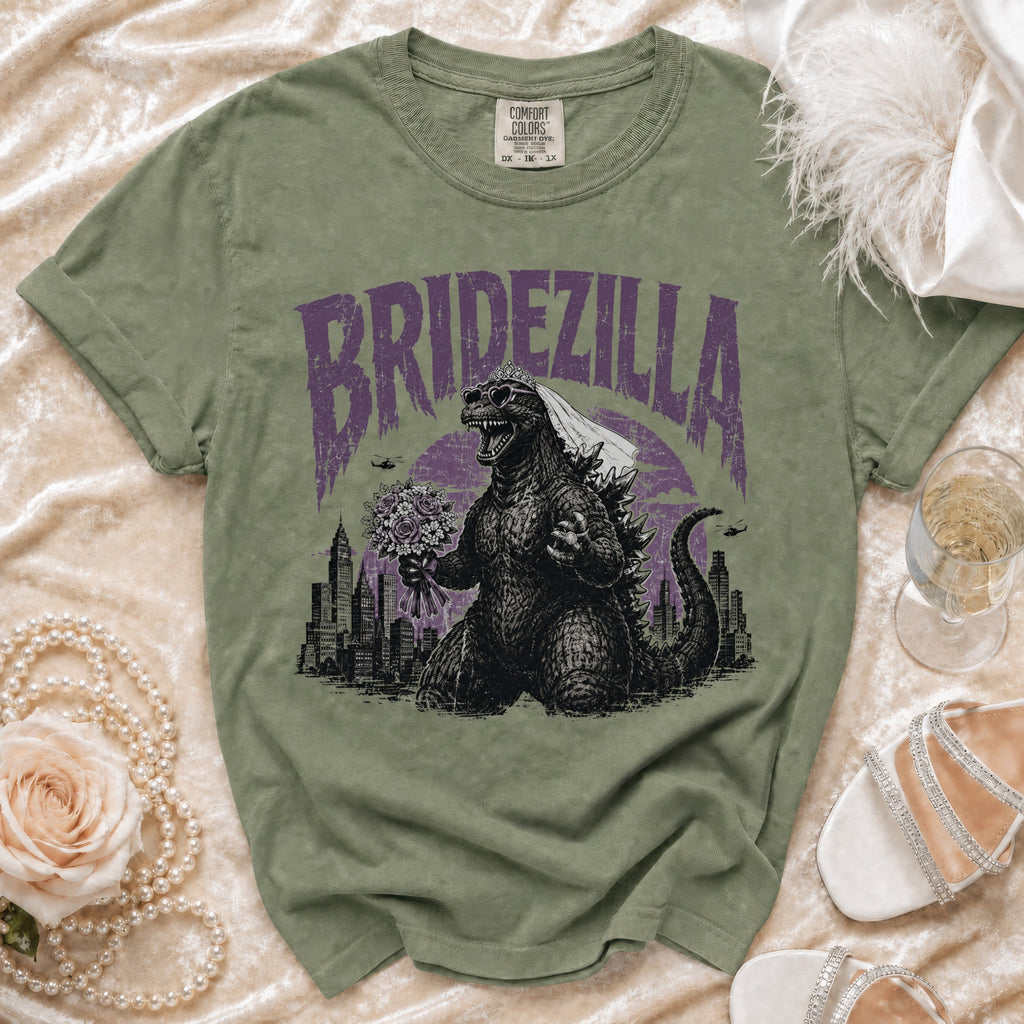 Olive green t-shirt with "Bridezilla" text, Godzilla wearing a veil and sunglasses, holding flowers.