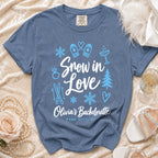 Blue Comfort Colors t-shirt printed with white and light blue winter icons, "Snow in Love", and "Olivia's Bachelorette Park City, UT".