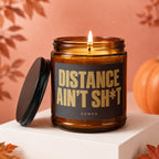Amber glass candle with lid off reads "DISTANCE AIN'T SH*T" and "VOWED".