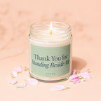 Lit candle in a glass jar with text "Thank You for Standing Beside Me"