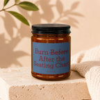 Amber jar candle with black lid and blue label reading "Burn Before After the Seating Chart"
