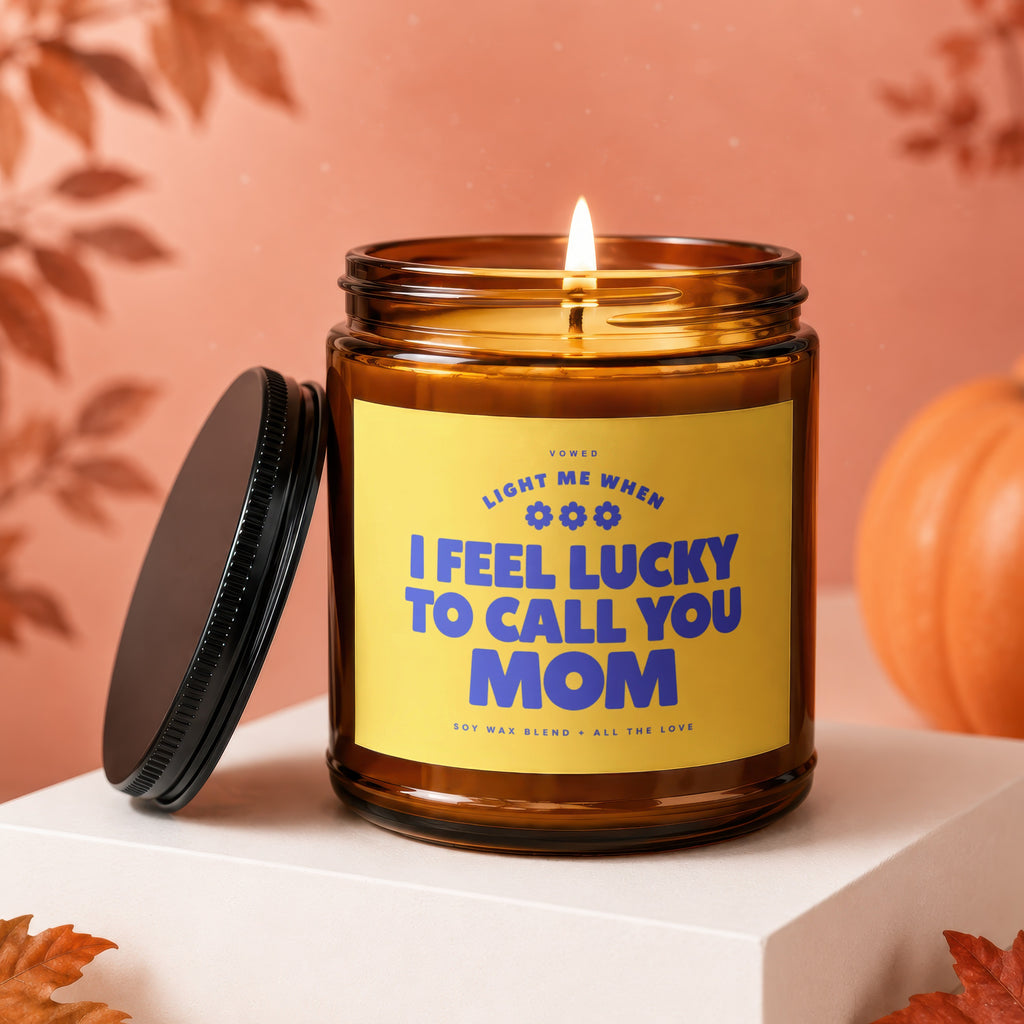 Amber jar candle with lit wick, yellow label reads "I feel lucky to call you Mom".