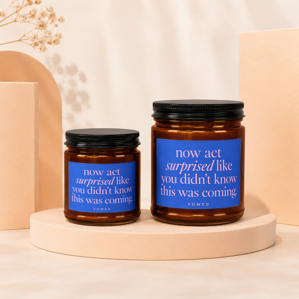 Two amber glass candles with black lids, each with a blue label.