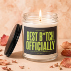 Glass candle with lit wick, black lid, and label stating "Best B*tch, Officially"