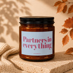 Amber glass candle with white label that reads "Partners in everything, VOWED".