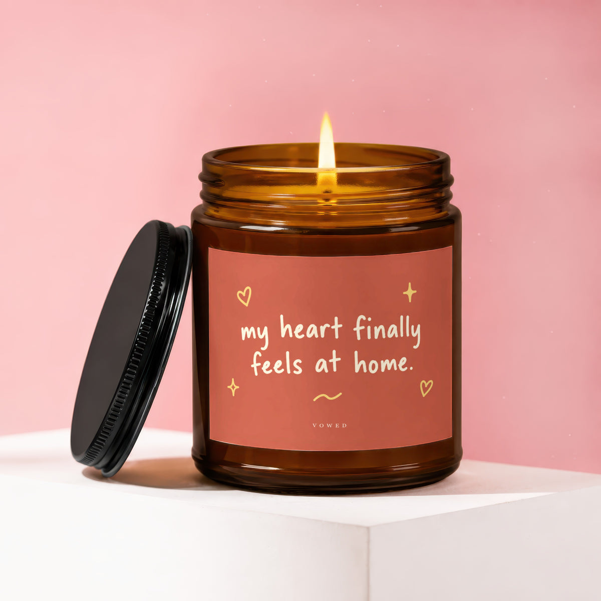 Amber glass candle with lit flame and label reading "my heart finally feels at home."