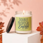 Glass candle with lit wick, lid off, label reads "DOUBLE PROPOSAL ENERGY VOWED".