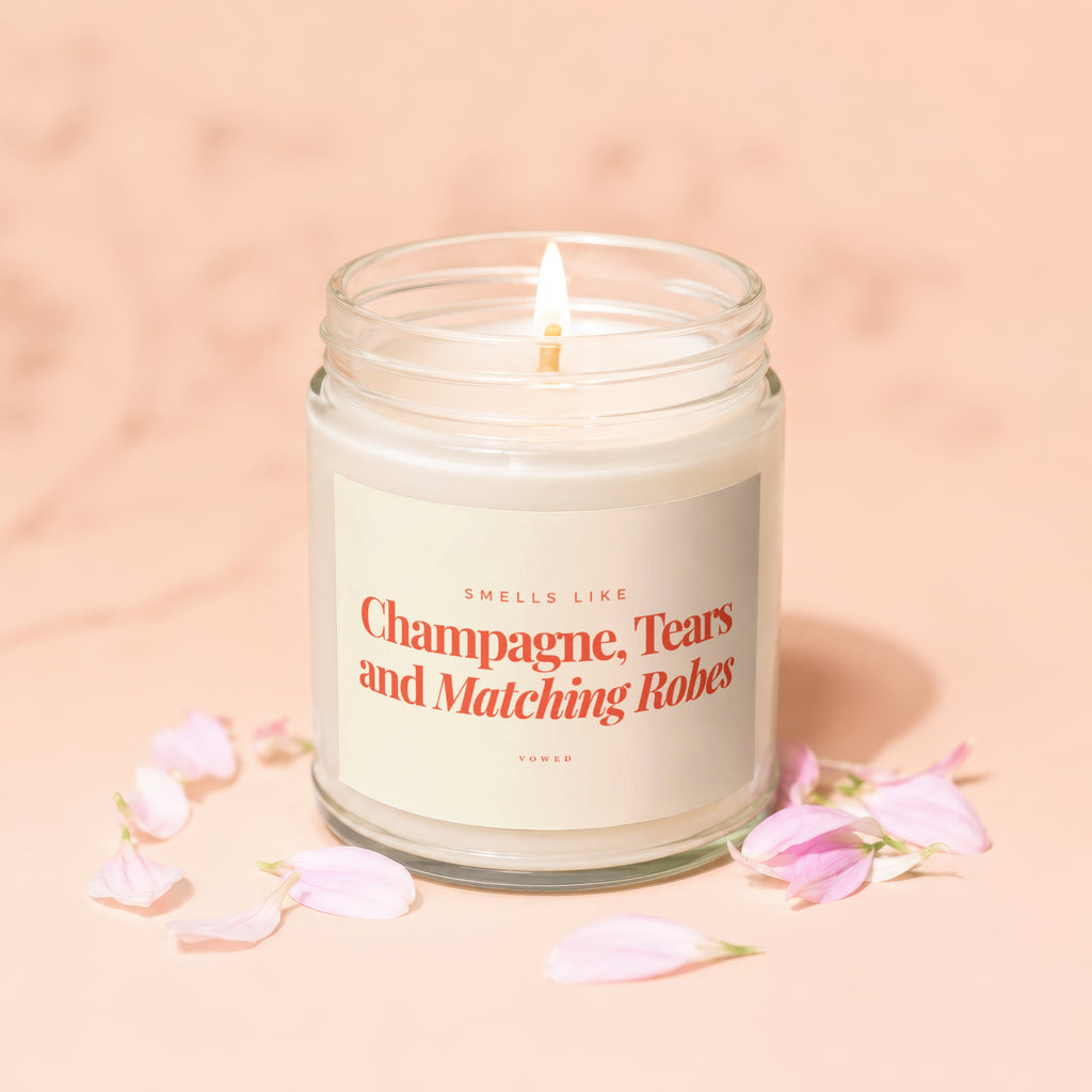 Candle with a lit wick, labeled "Champagne, Tears and Matching Robes."