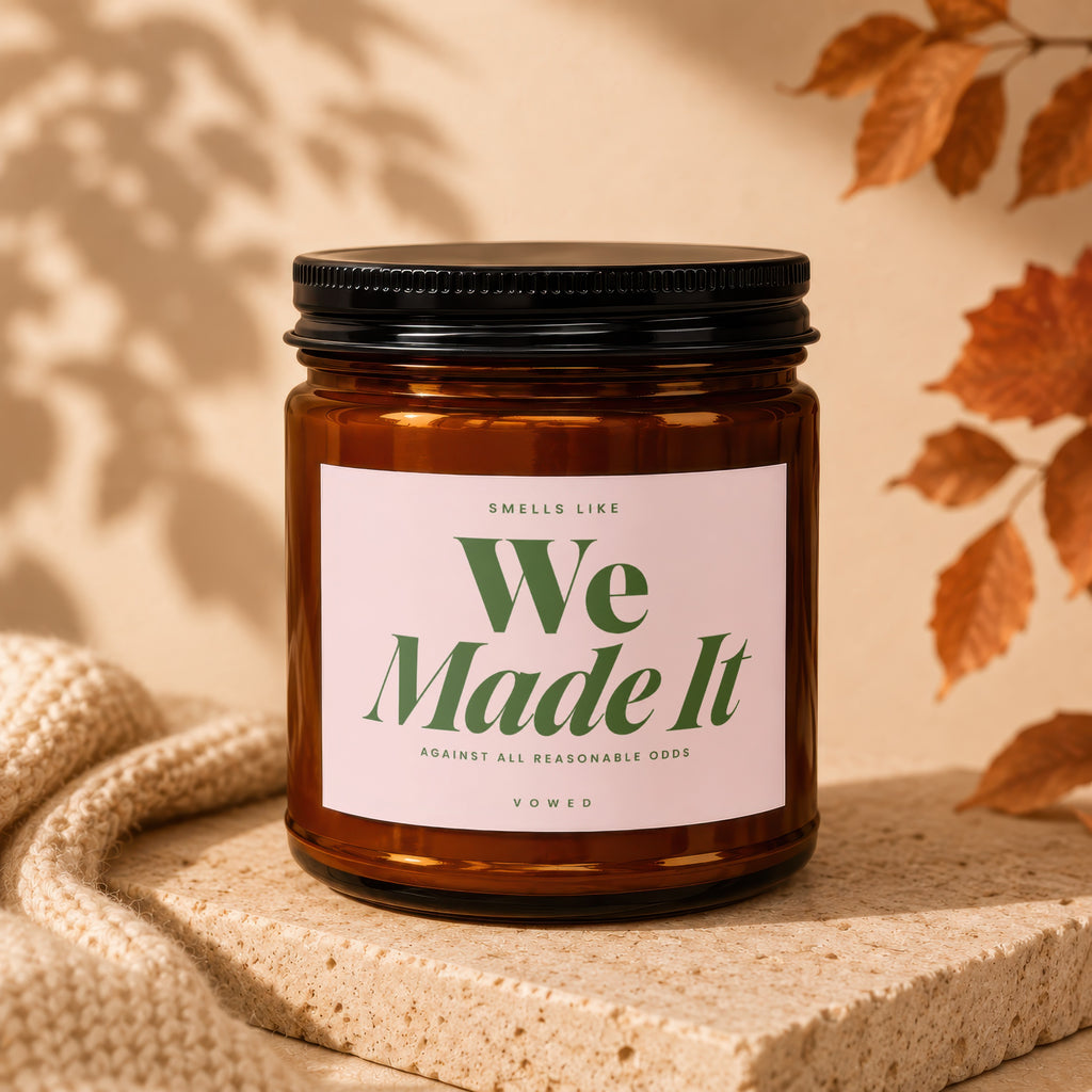 Amber jar candle with pink label reading "We Made It" and "Vowed."