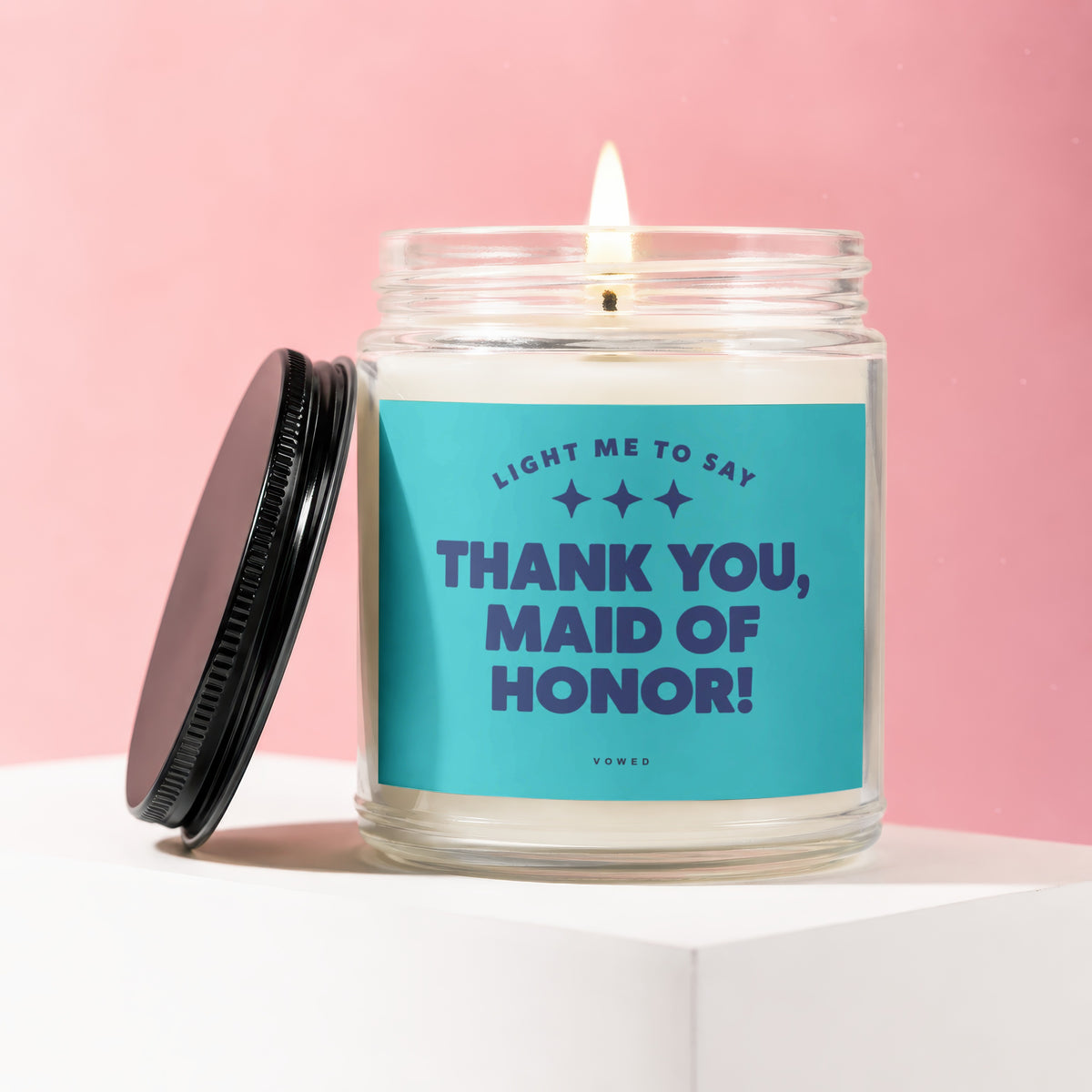 Glass candle with lit wick and label reading "Thank You, Maid of Honor!".