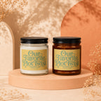 Two candles with "Our Favorite Plot Twist" text appear on a peach-colored pedestal.