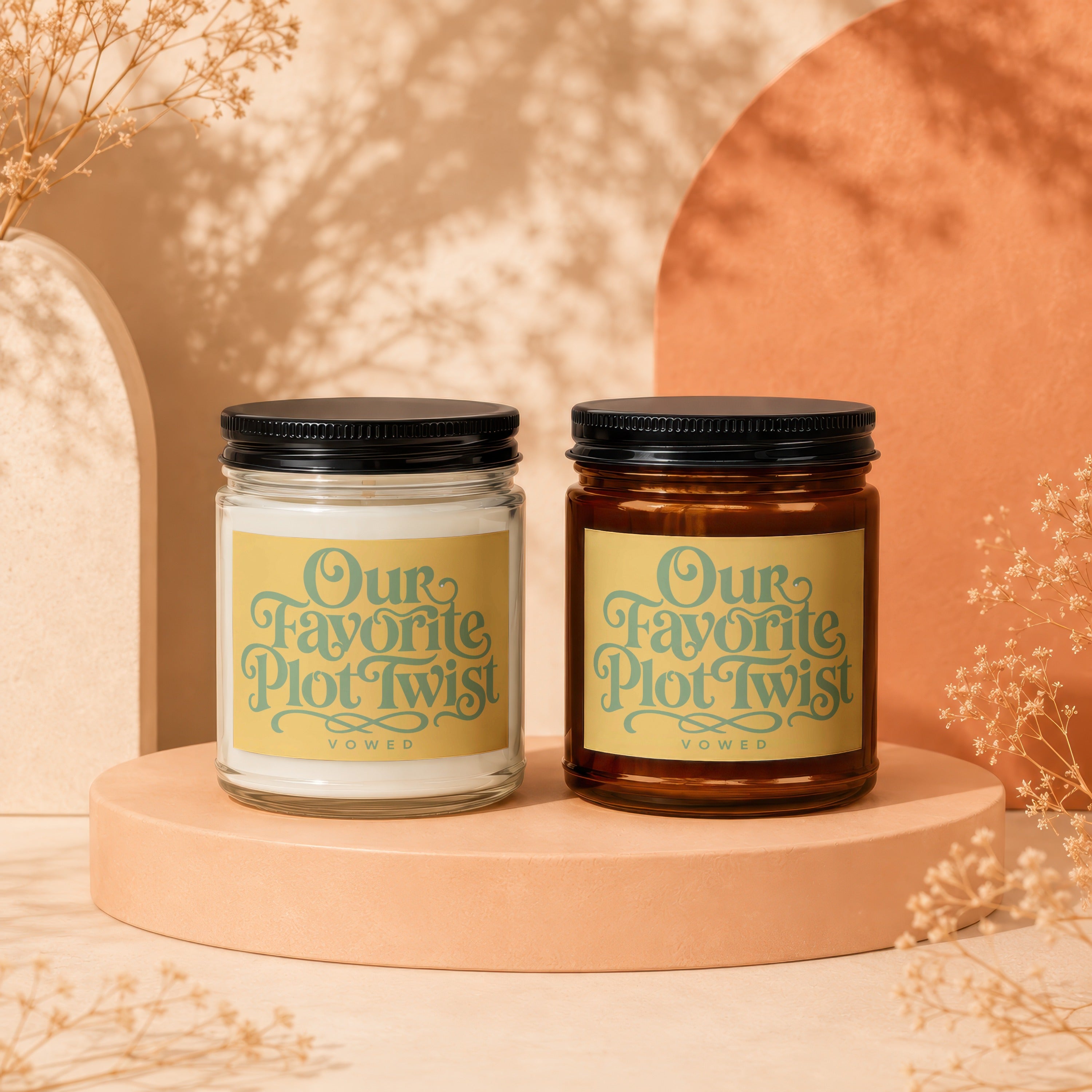 Two candles with "Our Favorite Plot Twist" text appear on a peach-colored pedestal.