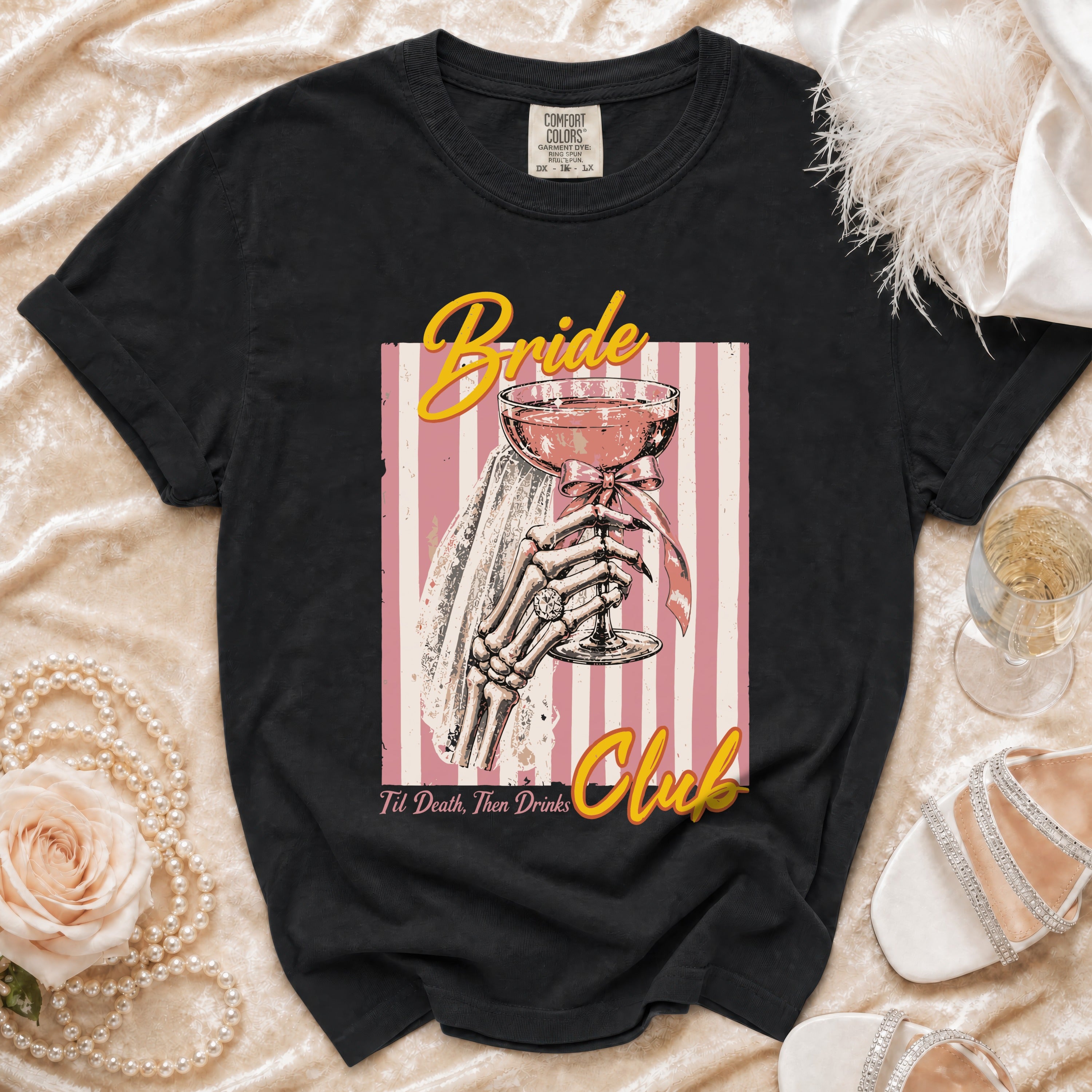 Black t-shirt graphic with skeleton hand holding a champagne glass, "Bride Club" text.