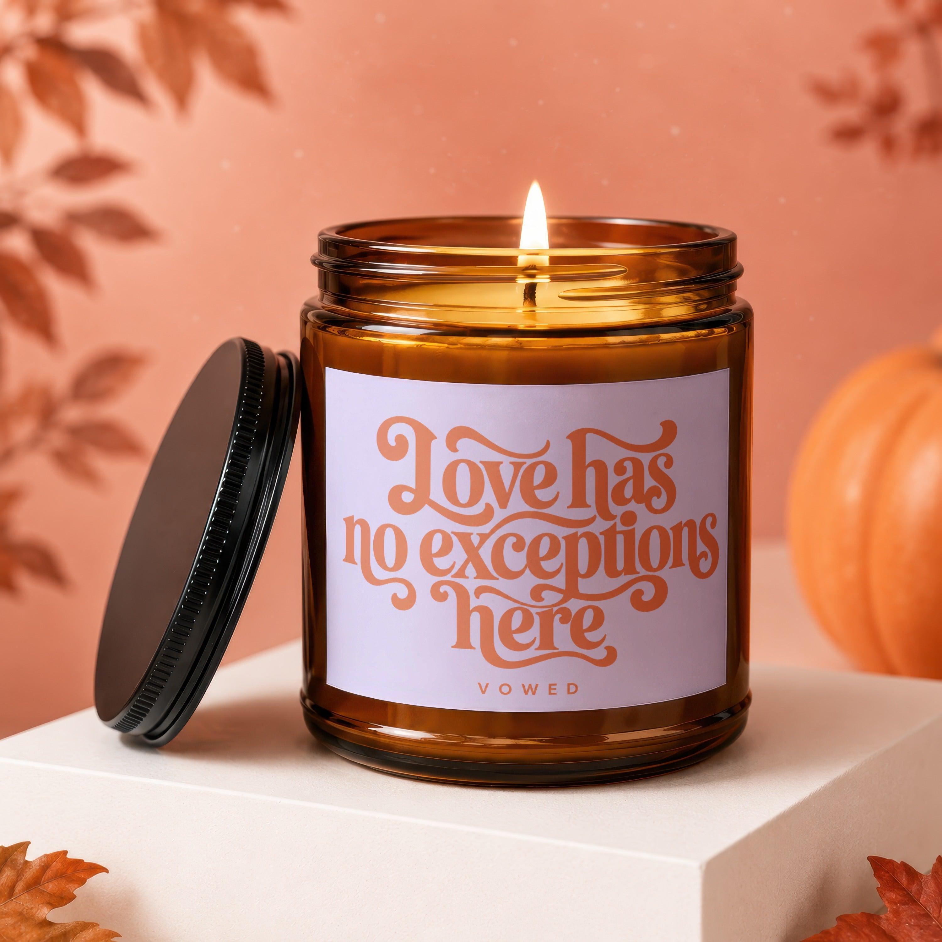 Amber jar candle with lit wick and label reading "Love has no exceptions here"