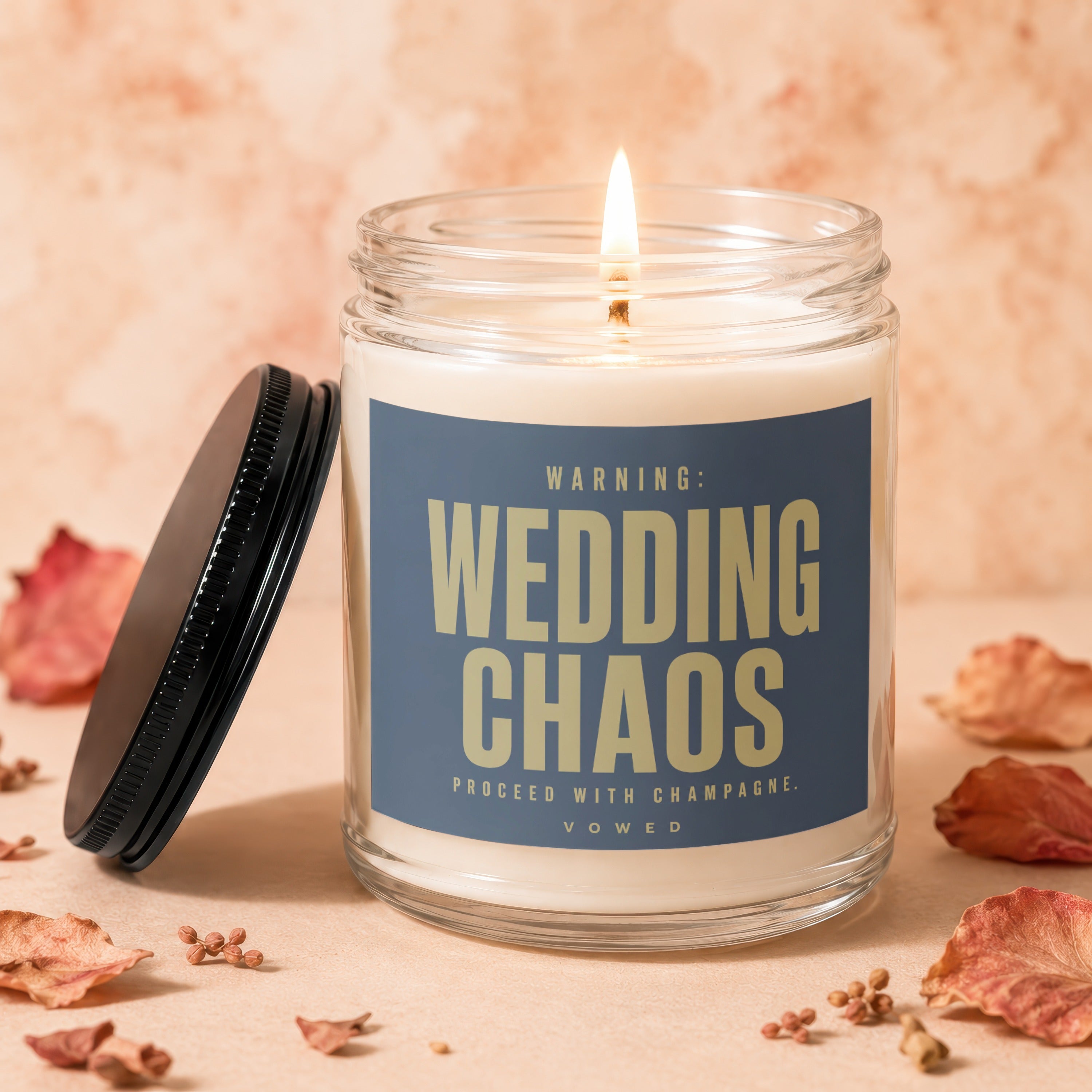 Lit candle in glass jar with "WARNING: WEDDING CHAOS" text and decorative elements.