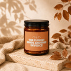 Candle with orange label reading "The Florist Sends Another Invoice"