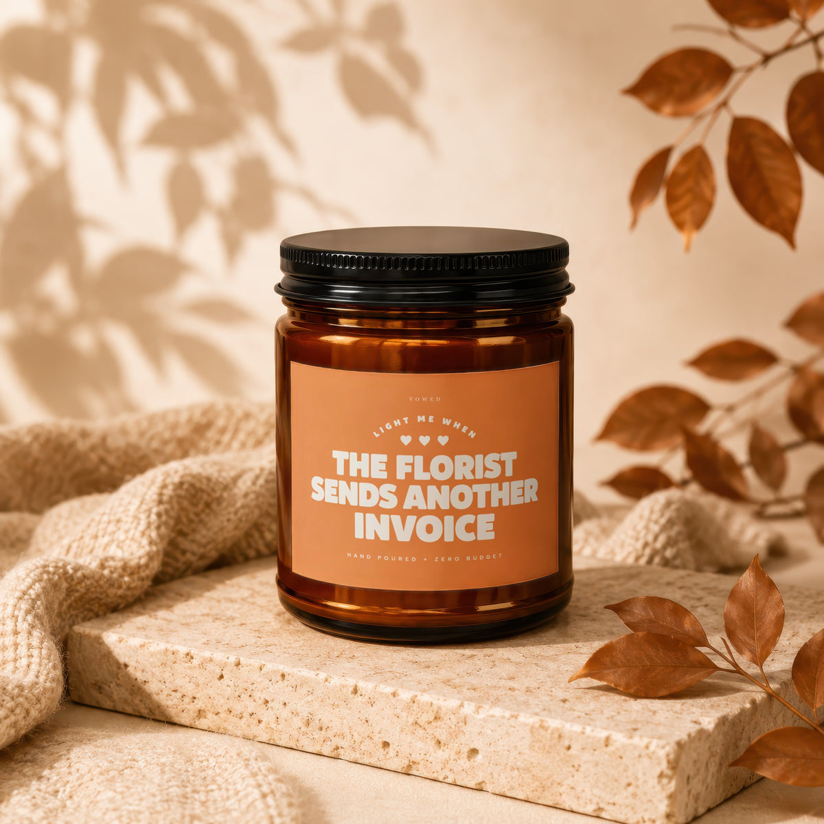 Candle with orange label reading "The Florist Sends Another Invoice"