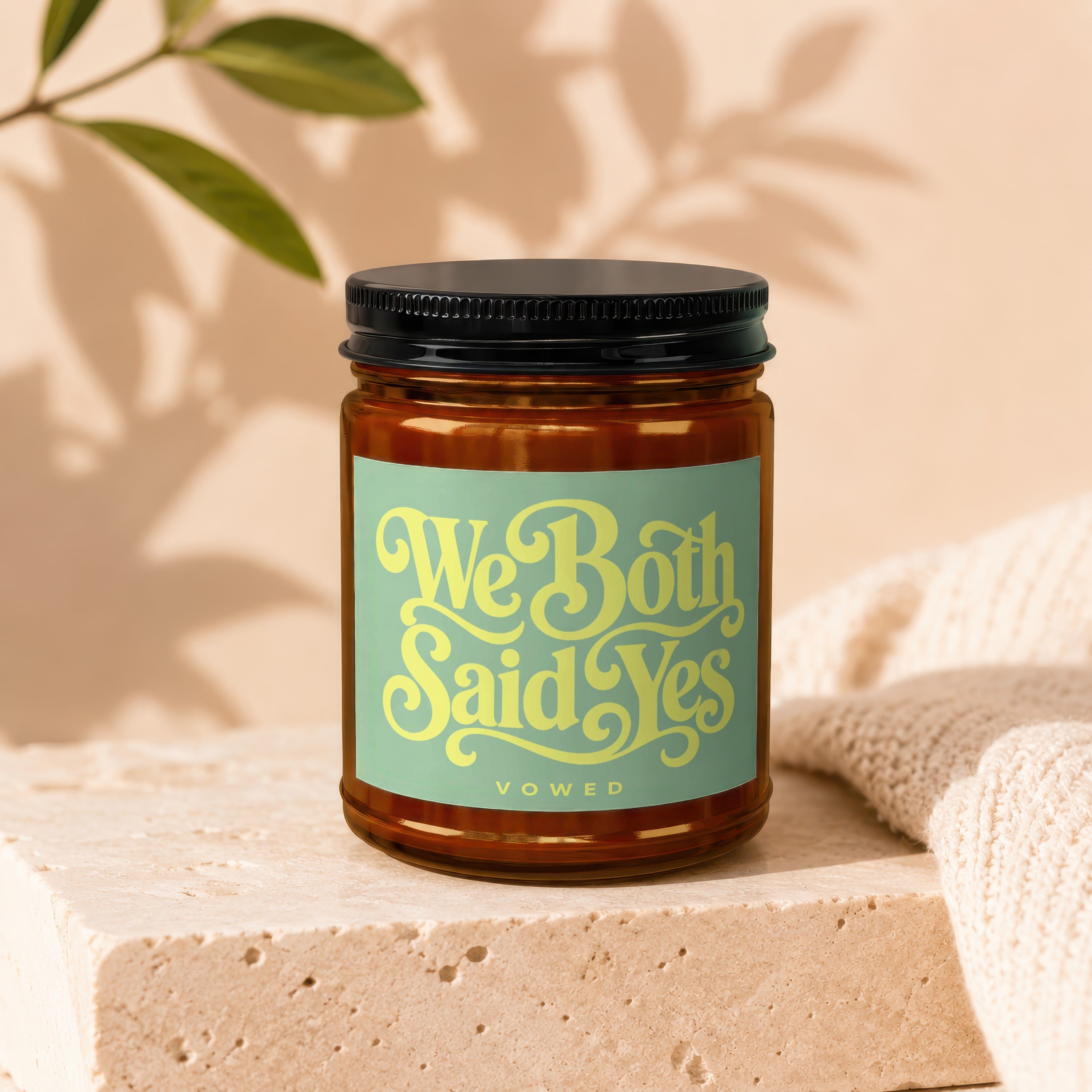 Amber jar candle with "We Both Said Yes" and "VOWED" text on a green label.