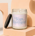 Candle with "Team [Lastname]" and "VOWED" text on label, black lid to the side.