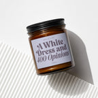 Amber glass candle with black lid, labeled "Smells Like A White Dress and 400 Opinions."