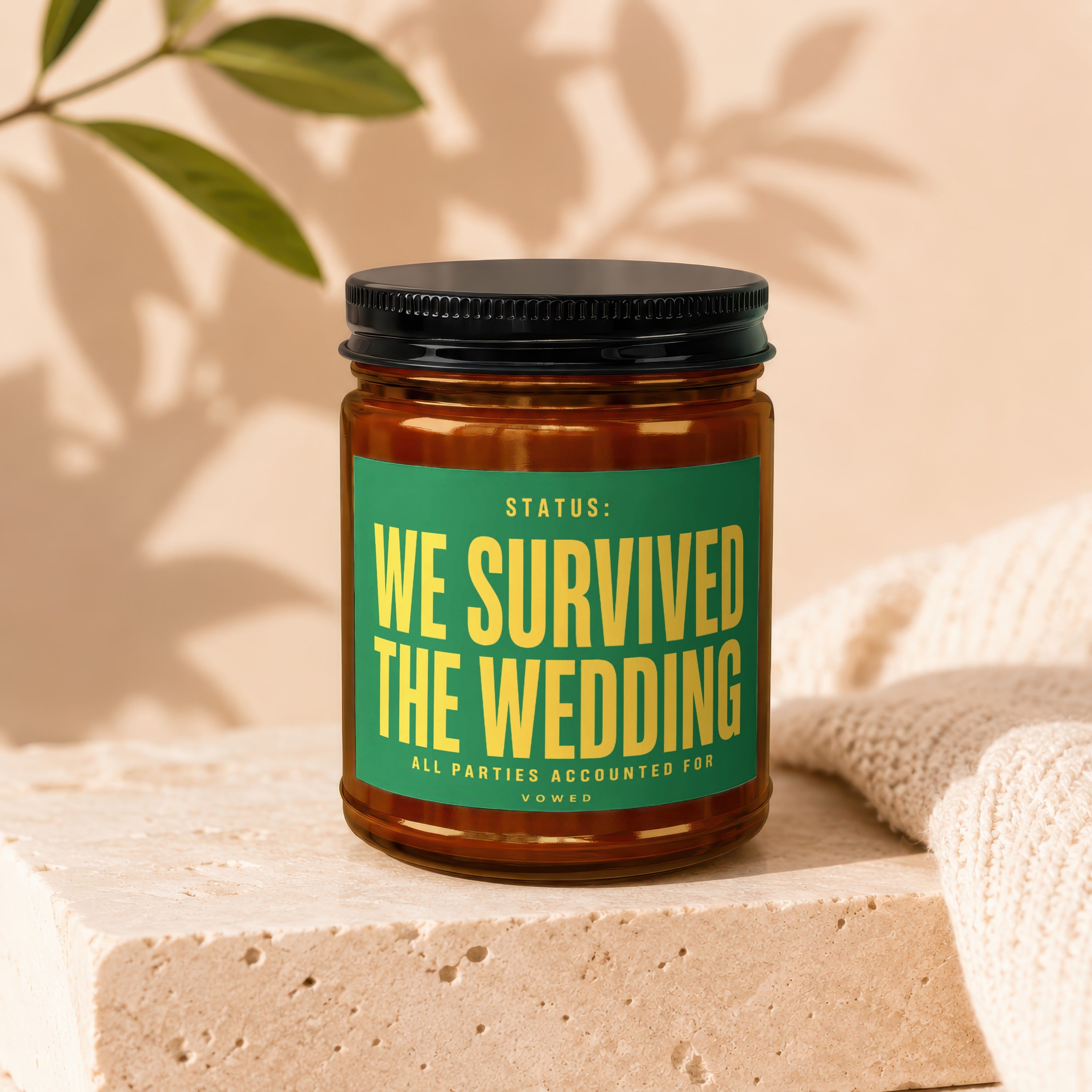 Amber jar candle with green label reading "Status: We Survived The Wedding"