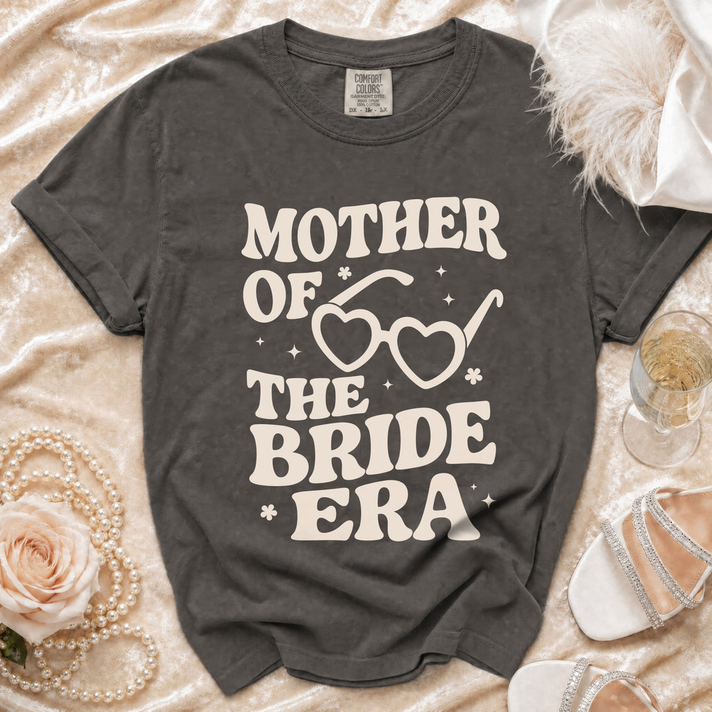 Dark grey t-shirt with cream text "Mother of the Bride Era" and heart-shaped glasses.
