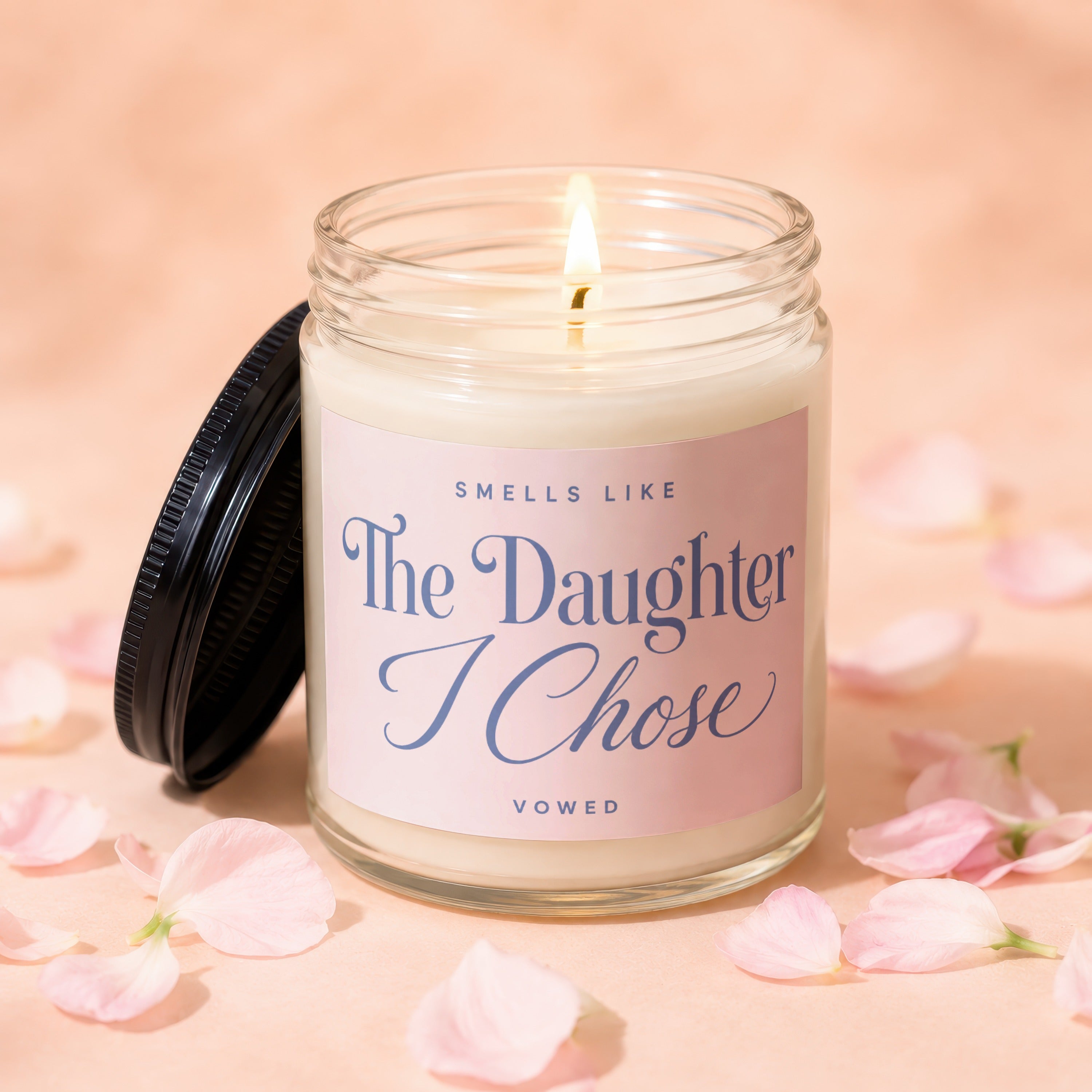 Lit candle with pink label reading "Smells Like The Daughter I Chose"