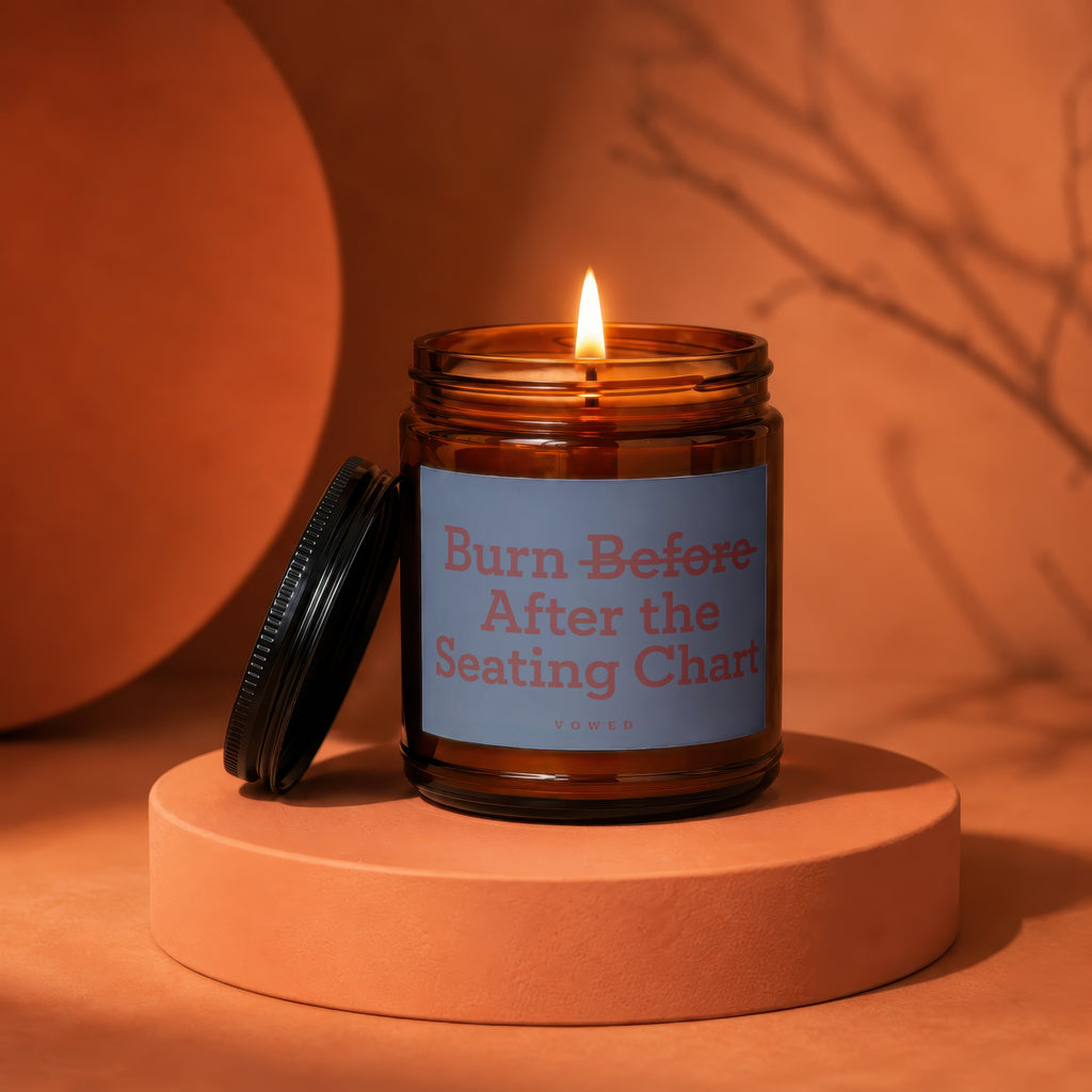Amber jar candle with lit wick, features label "Burn Before After the Seating Chart".