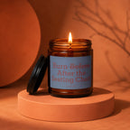 Amber jar candle with lit wick, features label "Burn Before After the Seating Chart".