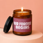 Amber jar candle with lit flame and the text "Our Forever Begins".