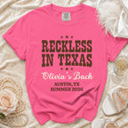 Pink t-shirt with "Reckless in Texas Olivia's Bach Austin, TX Summer 2026" text.