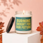 Glass jar candle with text "STATUS: BURNING BRIGHT FOR OUR FUTURE NO NOTES. NO REGRETS. VOWED".