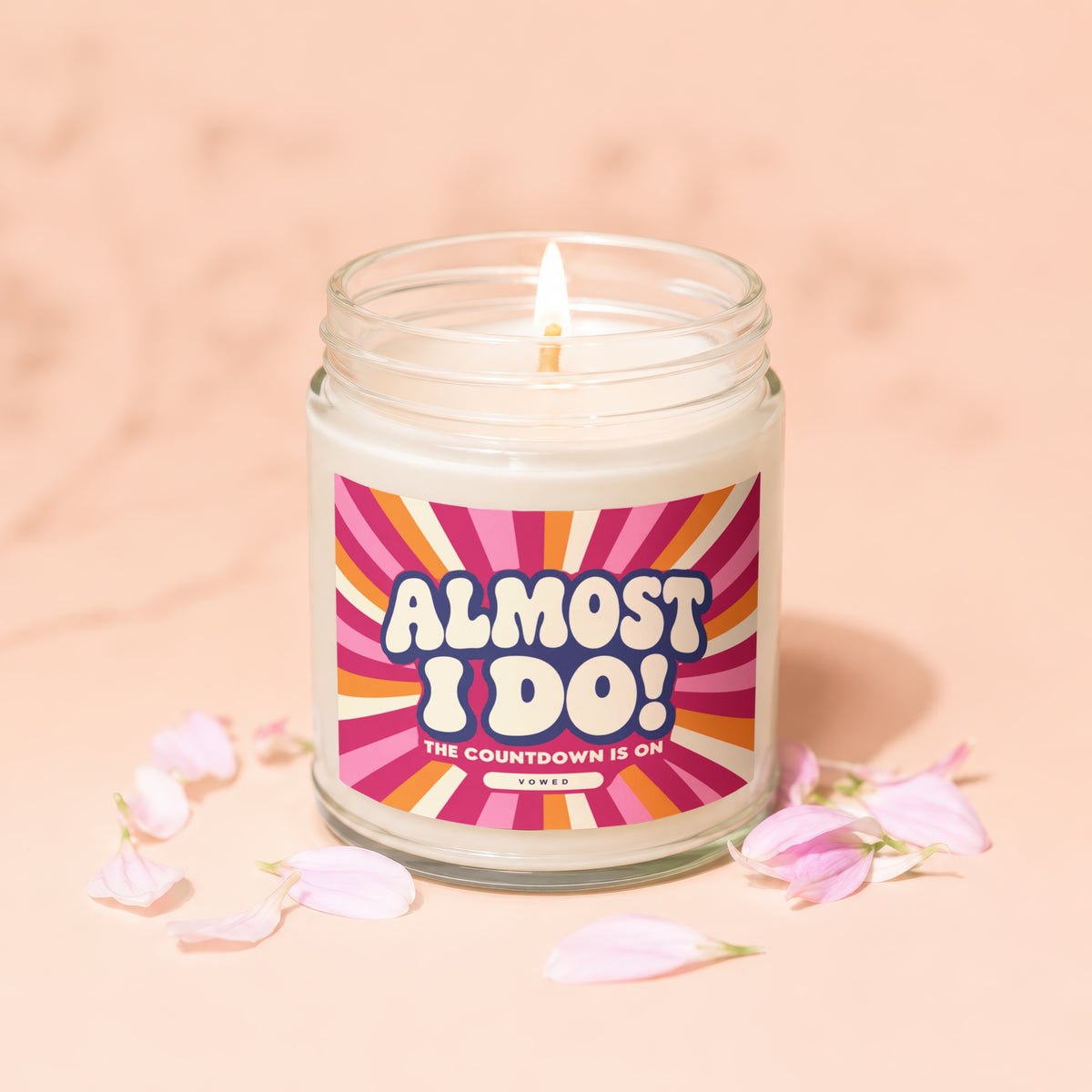 Glass candle with "Almost I Do! The Countdown Is On" label, surrounded by petals.