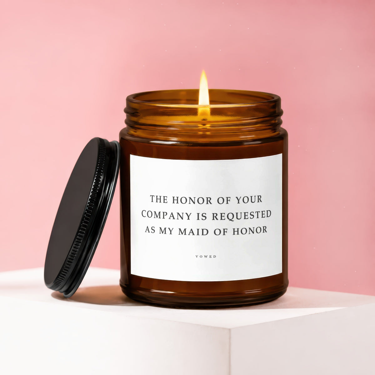 Amber jar candle with lit flame, asking "The honor of your company is requested as my maid of honor."