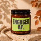 Amber candle in a glass jar with a black lid and a "ENGAGED AF. VOWED" label.